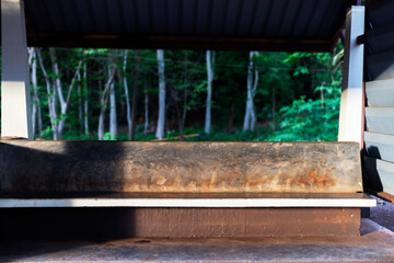 Seat bench at a train station in rural setting or country site with green back ground. Concrete bench in loft style under shadow from afternoon light