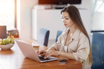 Pretty young woman working at home with laptop 
