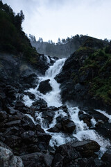 Latefossen Waterfall, unique waterfall epic powerful main big flow vertical photo in dark light. Twin waterfall in the Odda valley, Norway