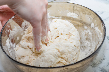 Thick dough is manually mixed in a transparent bowl.