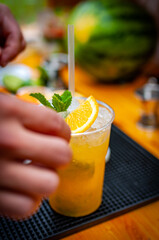 Cocktail preparation with orange, mint, maracuja and ice.