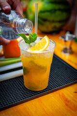 Cocktail preparation with orange, mint, maracuja and ice.