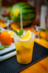 Cocktail preparation with orange, mint, maracuja and ice.