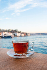 A cup of Turkish tea against the background of the cruise ship. Turkish tea served in the typical manner. Turkish tea in mug cup. Bosphorus
