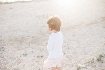 Little cute girl searching seashells on the sea beach