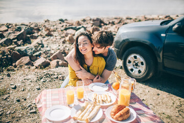 Picnic near the water. Happy family on a road trip in their car. Man and woman are traveling by the sea or the ocean or the river. Summer ride by automobile.