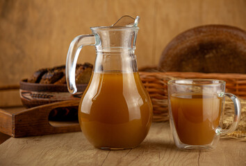Homemade bread kvass. Summer carbonated soft drink. Glass and carafe on a wooden table. Black...