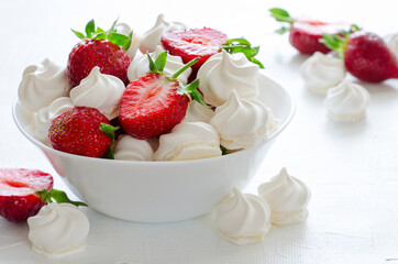 Fresh strawberries and meringues on white background