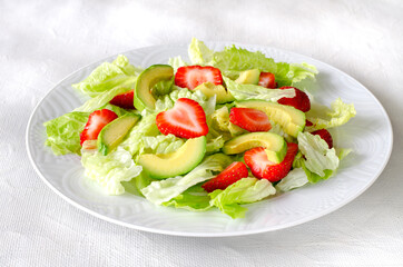Salad with avocado, strawberries and lettuce on white background