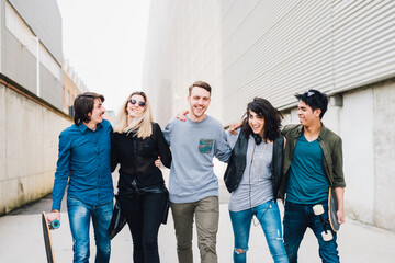 Obraz premium Group of friends multiethnic walking outdoor hugging - Five people friends walking outdoor together having fun