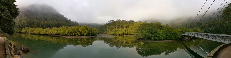 Beautiful morning panoramic view of Cockle creek with reflections of foggy sky, mountains and trees, Bobbin Head, Ku-ring-gai Chase National Park, New South Wales, Australia
