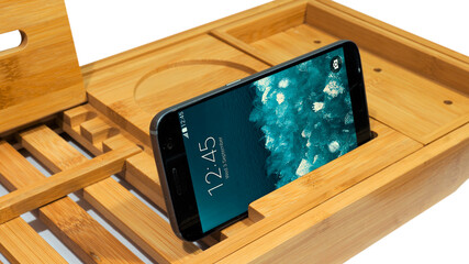 Close up extendable bamboo wooden bathroom tray of smart phone slot isolated on white background