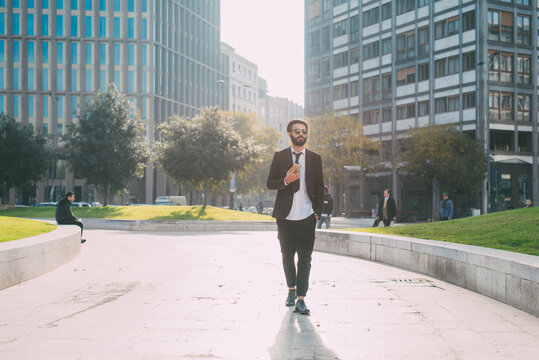 Young man contemporary businessman walking outdoor using smartphone - Modern businessman outdoors using cellphone remote working