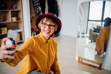 Adult woman indoors at home taking selfie - Cheerful woman indoors using smartphone