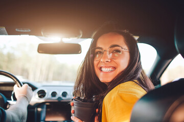 Travel, tourism -Beautiful woman with a couple of tea or coffee smiling while sitting on the seat in the car