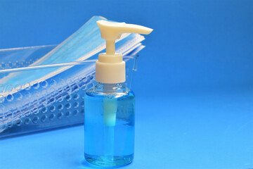 Disinfecting gel for hands and surgical masks on blue background