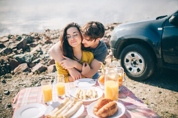 Picnic near the water. Happy family on a road trip in their car. Man and woman are traveling by the sea or the ocean or the river. Summer ride by automobile.