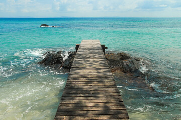 Wooden pier with blue sea and sky background. Beautiful ocean landscape. Travel, summer vacation and freedom, youth concept. Koh Munnork tropical island in Thailand.