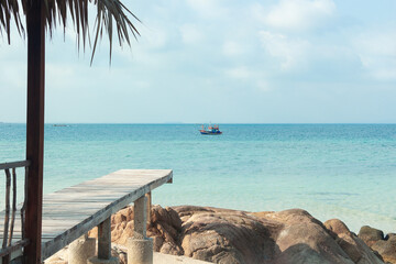Fishing wooden boat in the ocean. The view from private beach on tropical island. Sailing lifestyle. Koh Munnork island in Thailand. 