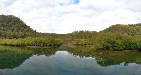 Fototapeta na wymiar Beautiful morning panoramic view of Cockle creek with reflections of foggy sky, mountains and trees, Bobbin Head, Ku-ring-gai Chase National Park, New South Wales, Australia