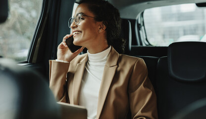 Businesswoman talking on phone while traveling by a cab