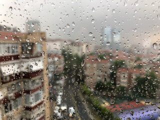 rain drops on a window pane against city view