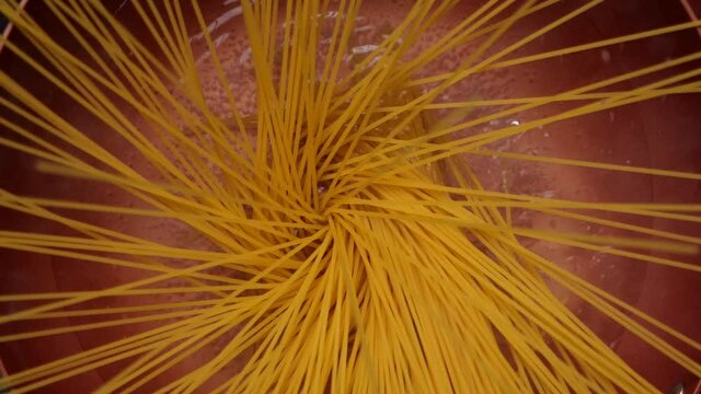 Throwing spaghetti pasta into hot water in a pan, Slow motion