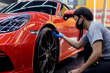 Car service worker polishing car wheels with microfiber cloth.