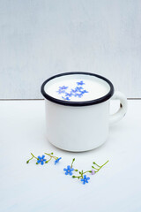 Enameled mug with milk. Blue flowers.