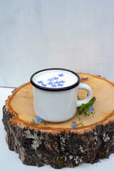 Enameled mug with milk. Blue color. Wooden background.