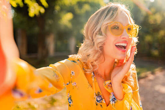 portrait of beautiful blond stylish white teeth smiling woman in yellow blouse wearing sunglasses making selfie photo, colorful summer fashion trend, bright spring sunny day, positive happy mood