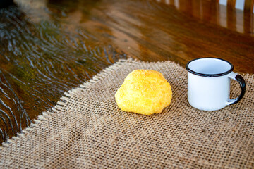 Brazilian cheese bread with coffee mug on jute towel and rustic table