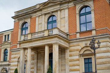 Fassade des Festspiel Gebäudes - Wagner Festspielhaus Bayreuth. Orangene Steine, Blaue Fensterrähmen und Sandsteine. Säulen halten Balkon. Bayreuth in Bayern, Deutschland. 
