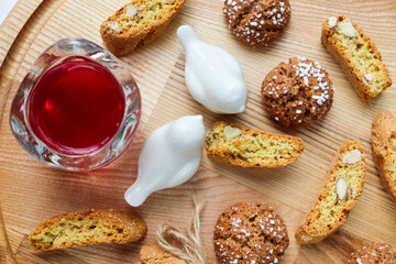 Traditional italian cantuccini cookies with almonds and dried cranberries with a glass of red sweet wine on a wooden background. Home baking concept.