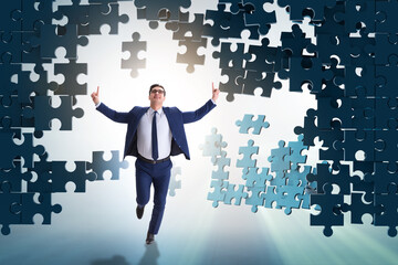 Businessman breaking the wall of jigsaw puzzle