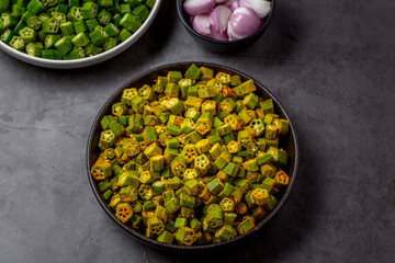 chopped raw okra mixed with turmeric powder in a bowl, preparation for indian vegetable bhindi fry