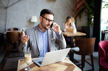 Happy confident businessman sitting with laptop at office