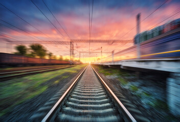 Fototapeta na wymiar Railroad and beautiful sky with clouds at sunset with motion blur effect in summer. Industrial landscape with freight train, railway station and blurred background. Railway platform in speed motion
