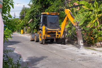 Excavator breaking and drilling the concrete road for repairing. Large pneumatic hammer mounted on the hydraulic arm of a construction equipment.Construction Vehicles repairing road.drilled jackhammer