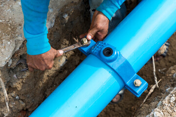 Man using a large wrench on water pipes. Construction site with new Water Pipes in the ground....