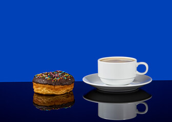Tasty donut and white cup of coffee with coffee on a blue background with reflection