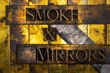 Smoke and Mirrors text formed with real authentic typeset letters on vintage textured silver grunge copper and gold background