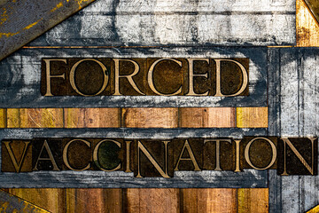 Forced Vaccination text formed with real authentic typeset letters on vintage textured silver grunge copper and gold background