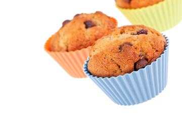 Three chocolate chip and banana muffins in silicon pastel cases, isolated  on white background