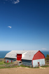 Fototapeta na wymiar Traditional style tin barn overlooking the sea, La Malbaie, Quebec Province, Canada. Space for your text.