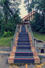 A strairway accross the bushes and tree towards the a building on the hill