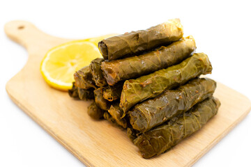 Sarma is a Turkish Traditional famous food on grape leaves. Turkish foods;(yaprak sarma dolma)  stuffed leaf stuffed rice on wooden plate, served with lemon