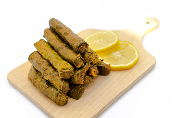 Sarma is a Turkish Traditional famous food on grape leaves. Turkish foods;(yaprak sarma dolma)  stuffed leaf stuffed rice on wooden plate, served with lemon