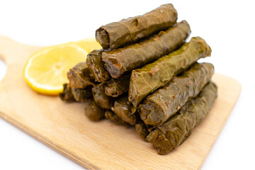 Sarma is a Turkish Traditional famous food on grape leaves. Turkish foods;(yaprak sarma dolma)  stuffed leaf stuffed rice on wooden plate, served with lemon