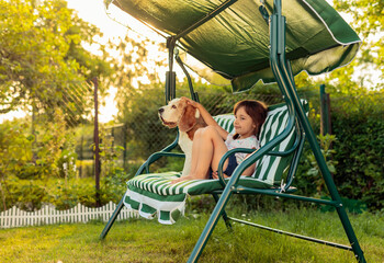 Little girl is resting on a bench with her dog.